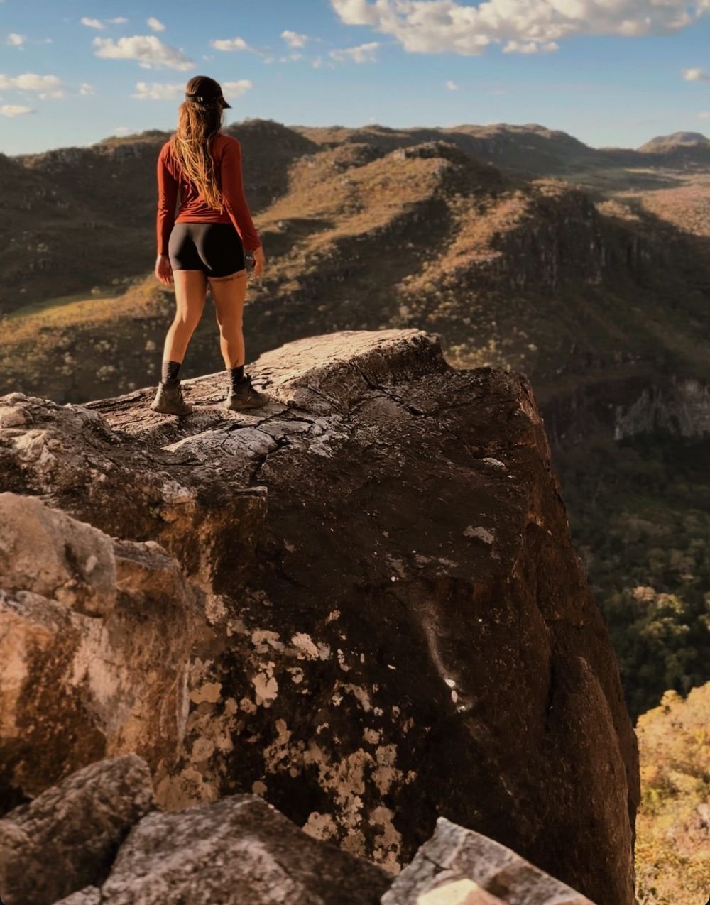 Visitante no alto de uma pedra com a serra ao fundo